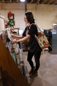 Girl in a getting a book in a book shelf with a colorful bag